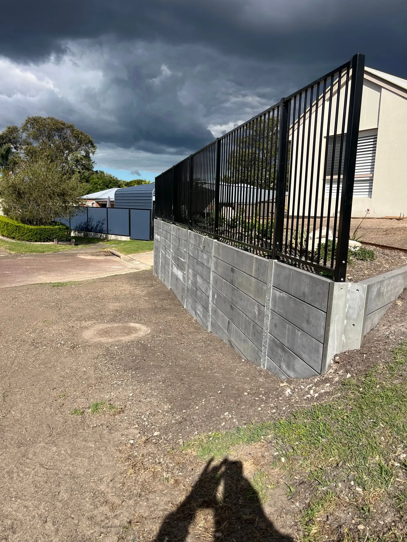 Corner of a concrete sleeper retaining wall with steel posts and fencing, Albany Creek