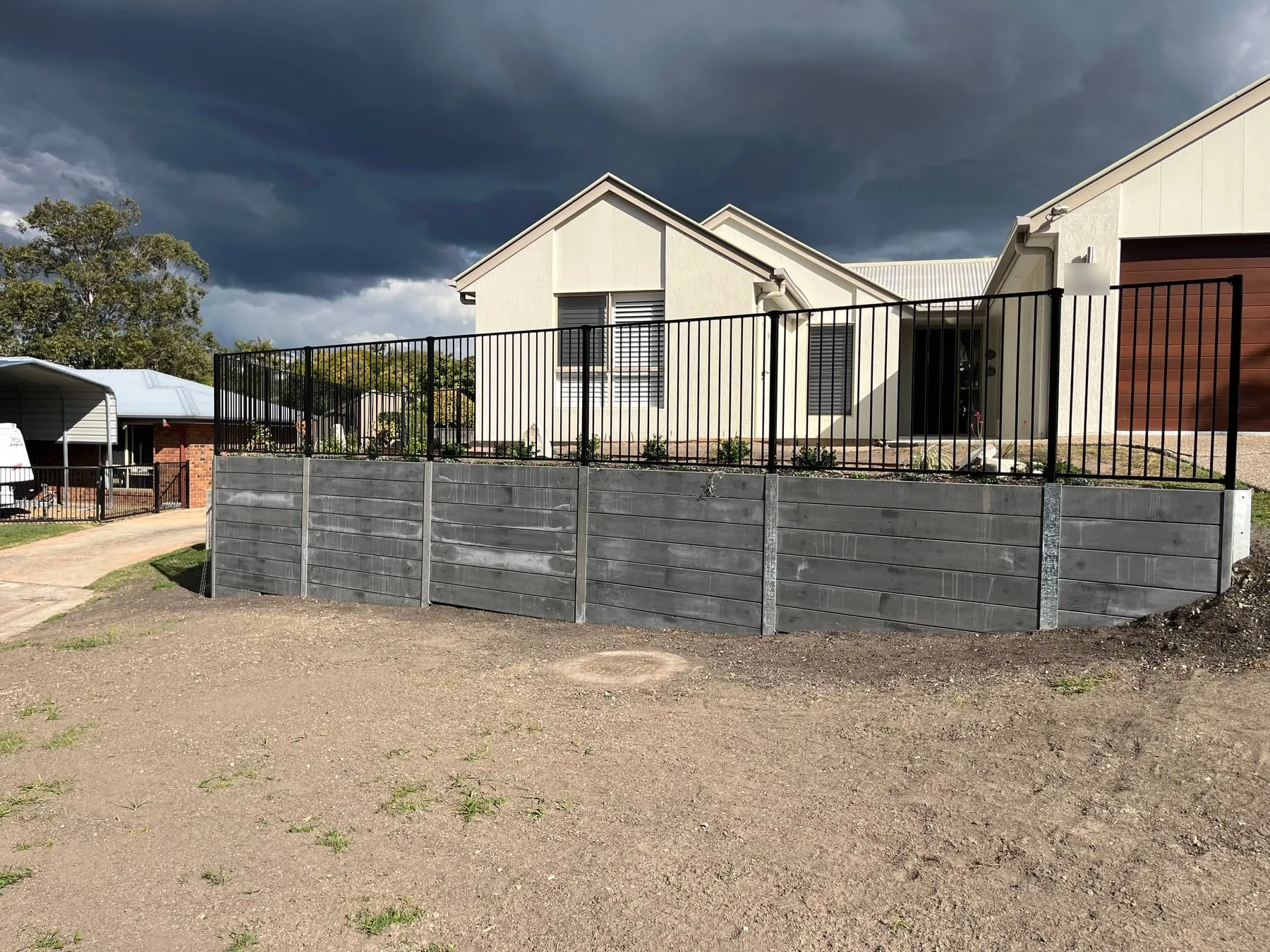 Grey concrete sleeper retaining wall with black pool style fencing, Albany Creek