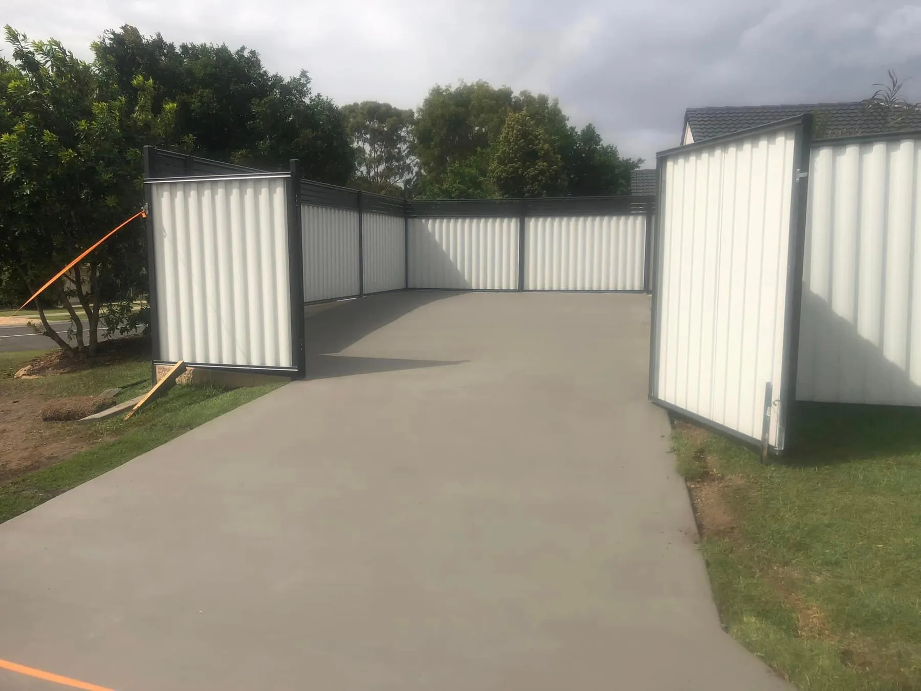 Wide concrete driveway poured between two sheds