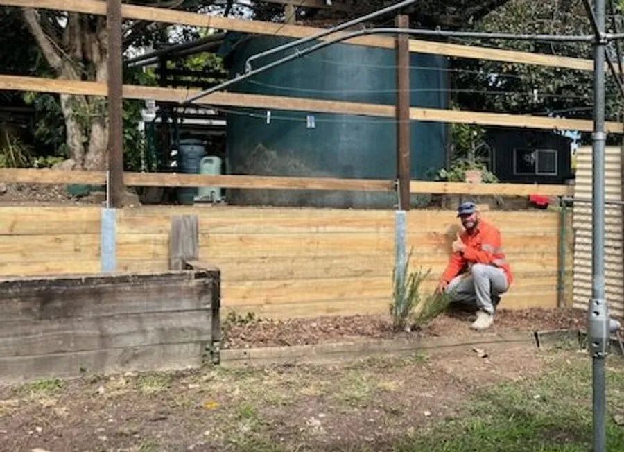 Scotty, owner of SC Hardscapes, on site beside a timber sleeper retaining wall