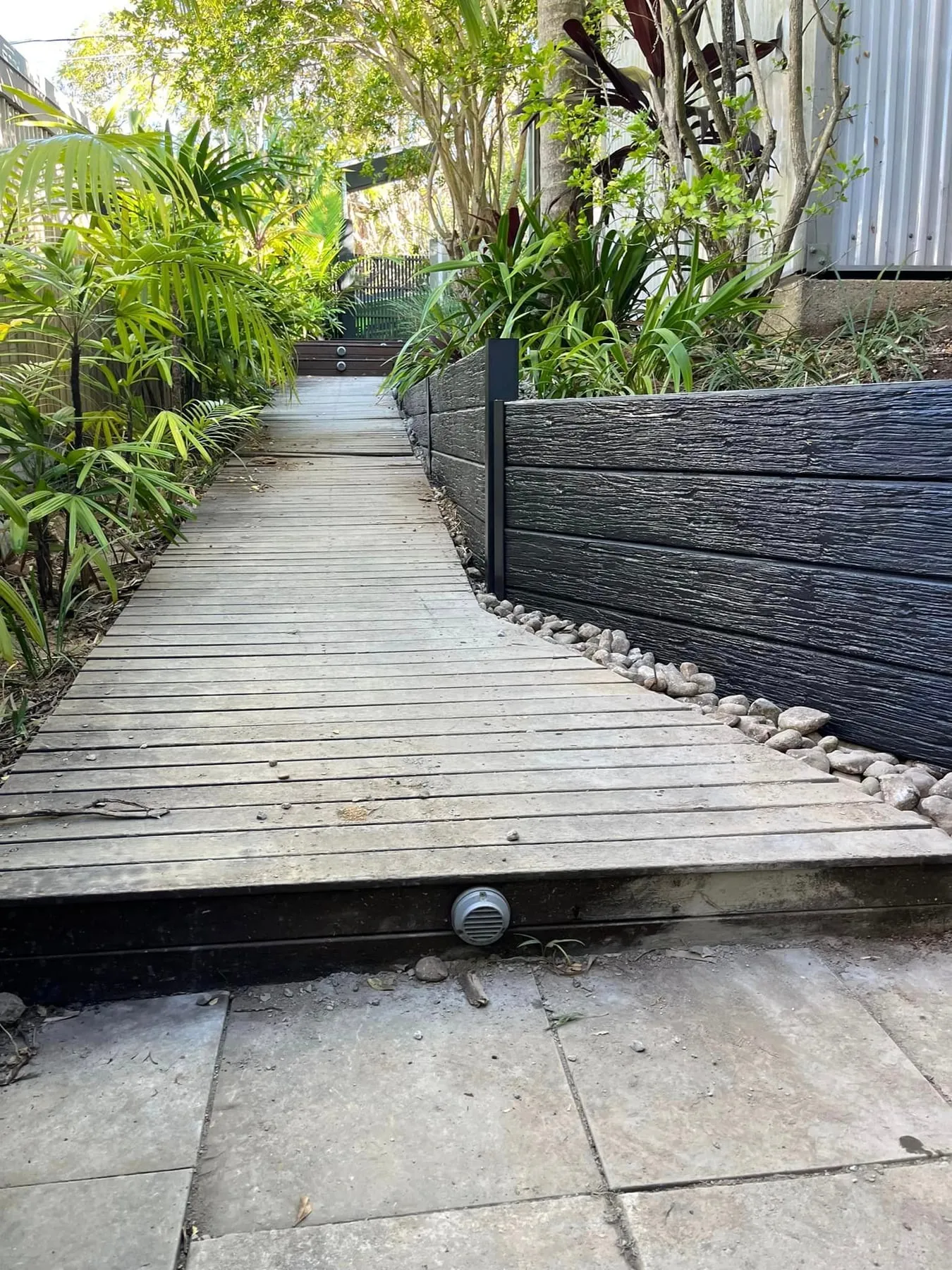 Charcoal concrete sleeper wall running along a paved courtyard