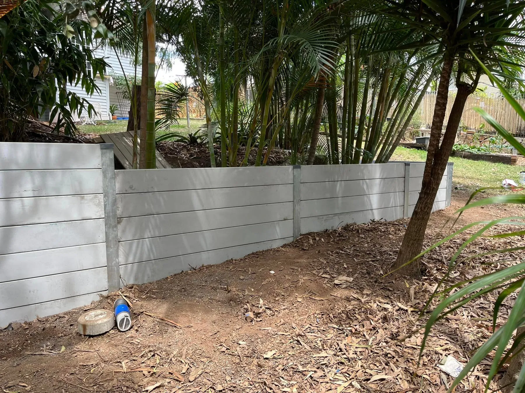 Grey concrete sleeper retaining wall in a palm garden