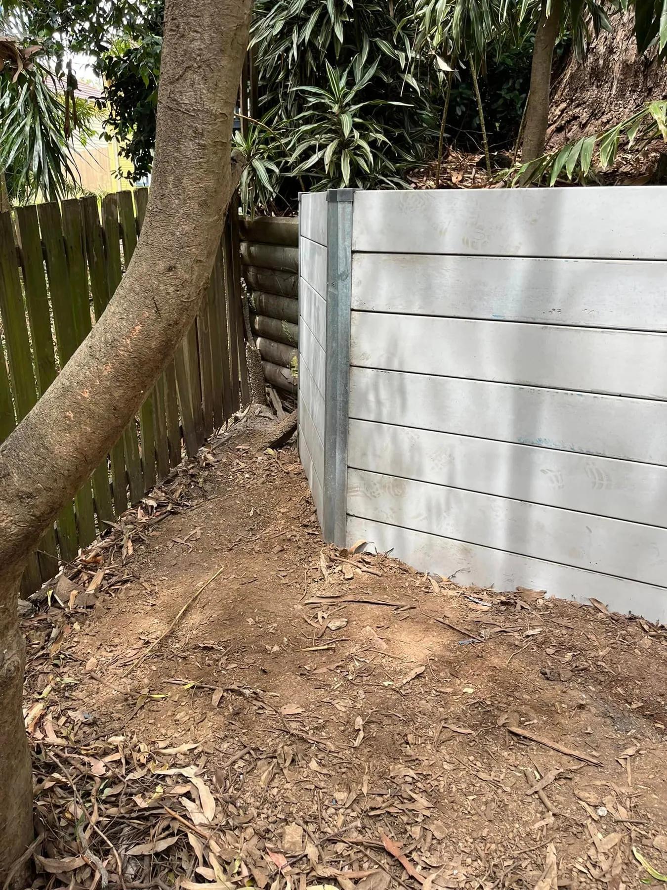 Grey concrete sleeper wall built around an established tree
