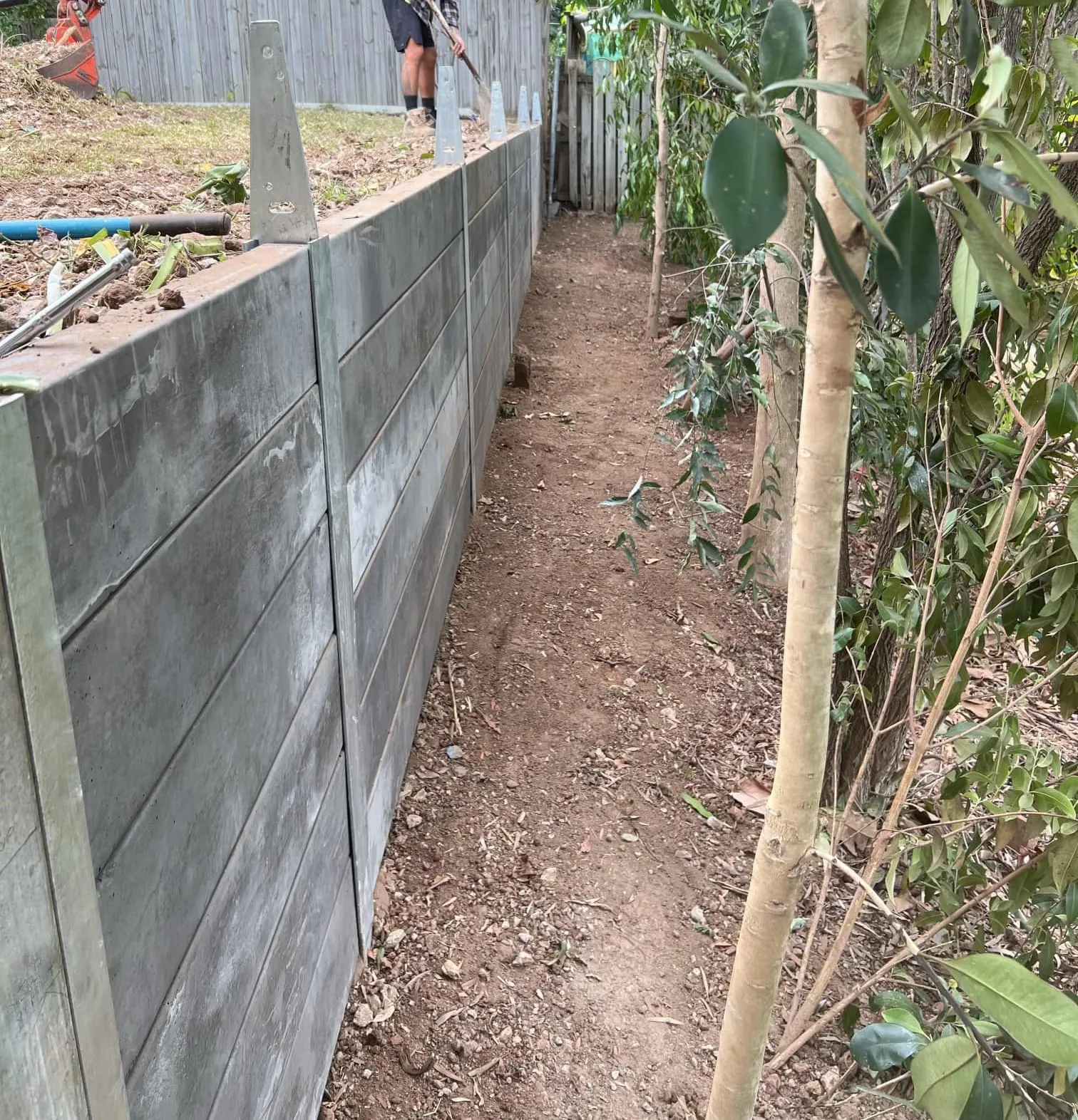 Concrete sleeper retaining wall below a timber fence