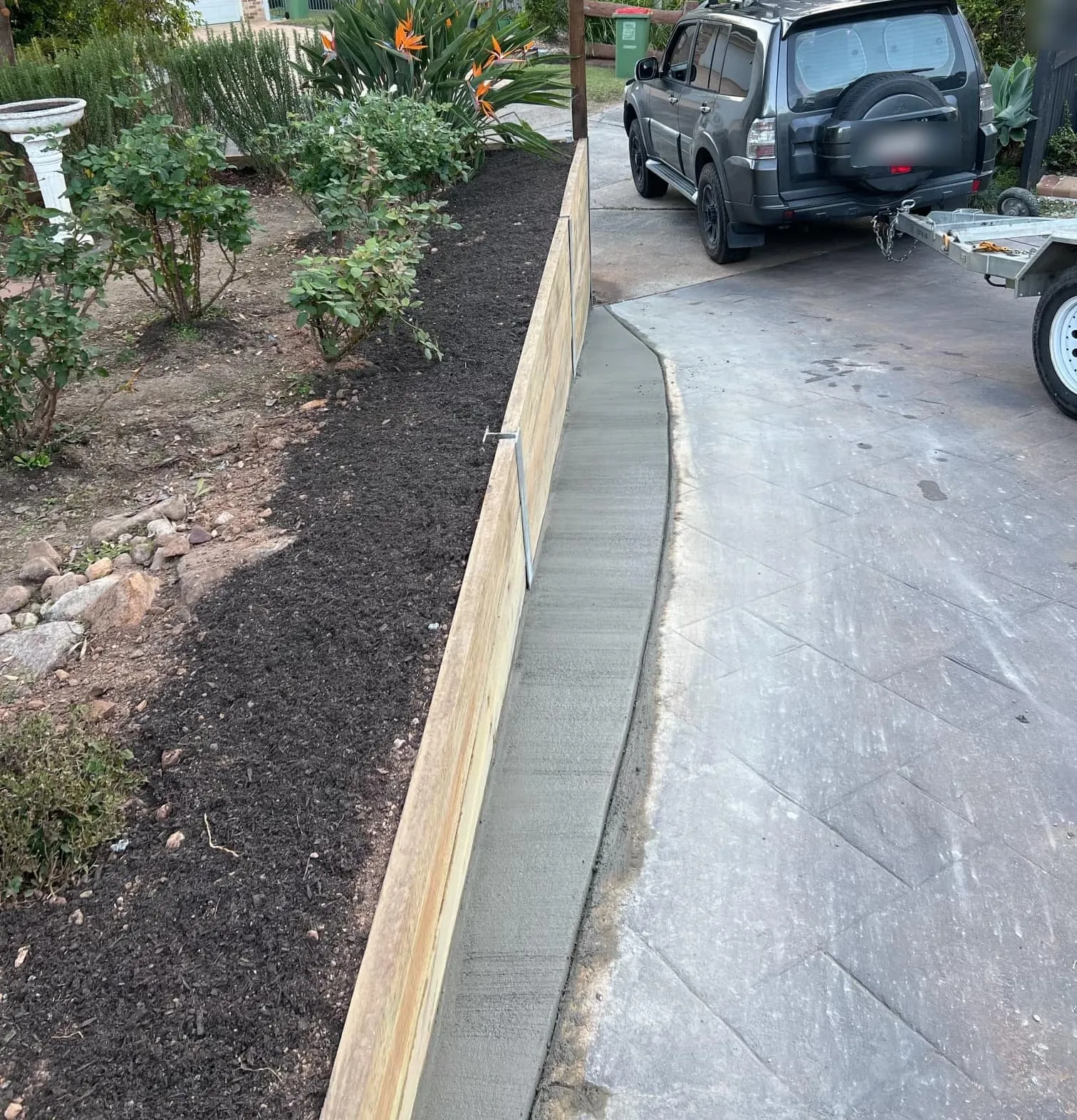Timber sleeper wall running alongside a concrete driveway